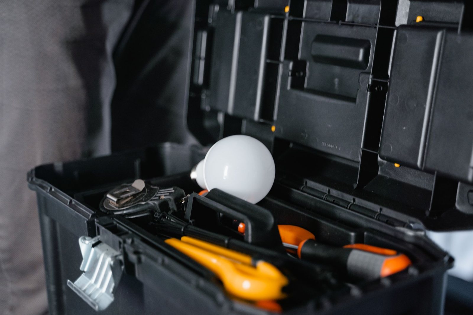 An electrician's working kit staged on a drop cloth before the first cut: hard tool cases open, hand tools and a cordless